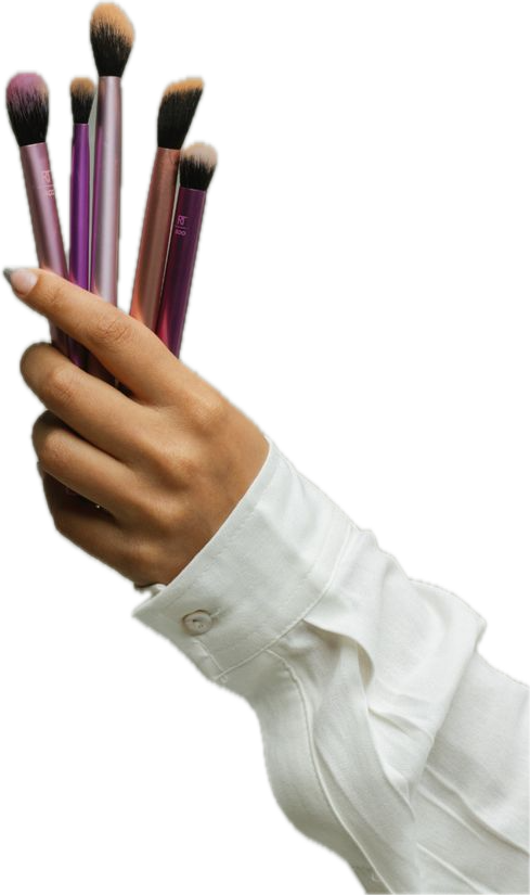 Mano sujetando varios pinceles de maquillaje en tonos rosa y morado